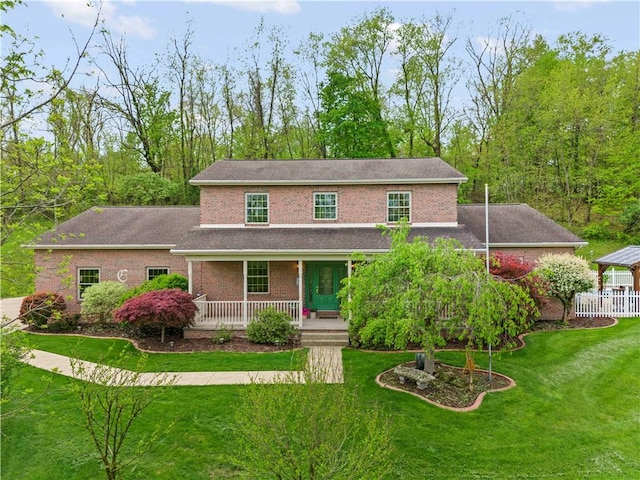 view of front of house featuring a porch, a front lawn, brick siding, and roof with shingles