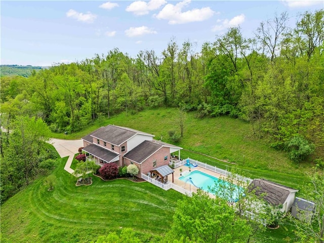 view from above of property featuring a pool area and a heavily wooded area