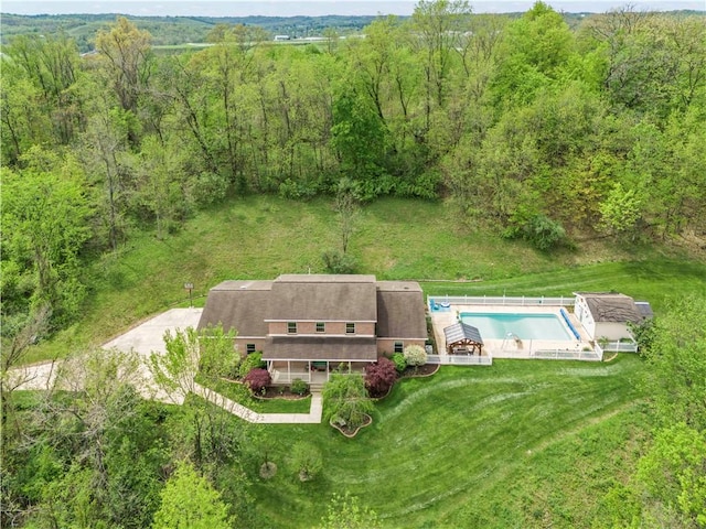 aerial view of property and surrounding area featuring a pool area and a forest