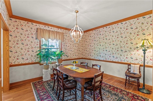 dining room with wallpapered walls, a chandelier, wood finished floors, crown molding, and baseboards