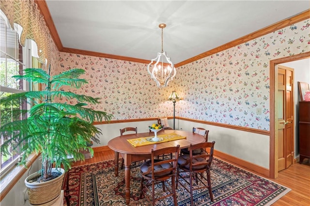 dining room with wallpapered walls, wood finished floors, a chandelier, baseboards, and ornamental molding