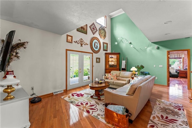 living area featuring french doors, hardwood / wood-style floors, baseboards, and high vaulted ceiling