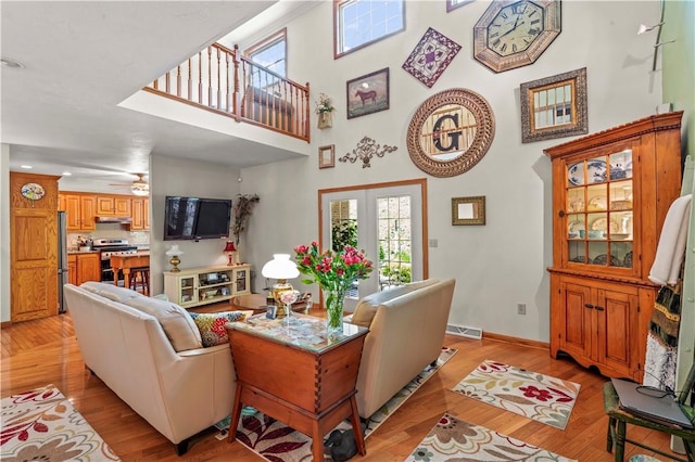 living room with light wood finished floors, a towering ceiling, baseboards, healthy amount of natural light, and recessed lighting