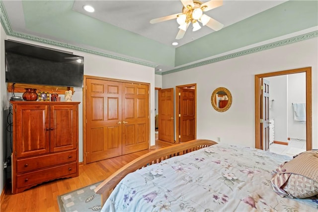 bedroom featuring a closet, light wood-type flooring, recessed lighting, a towering ceiling, and ensuite bath