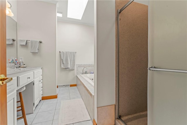 bathroom featuring a skylight, tile patterned floors, a bath, vanity, and a stall shower
