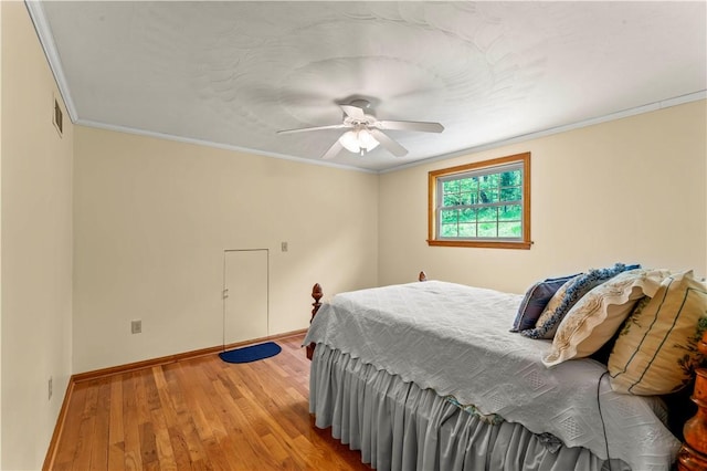 bedroom featuring wood finished floors, crown molding, a ceiling fan, and baseboards