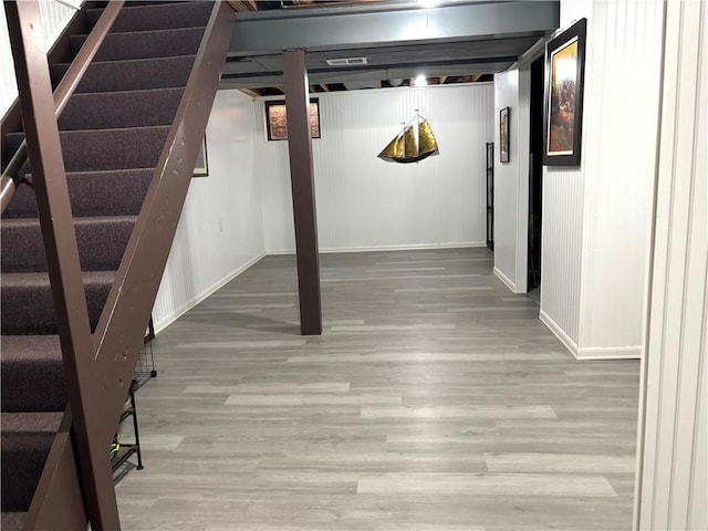 finished basement featuring wood finished floors, baseboards, and stairway