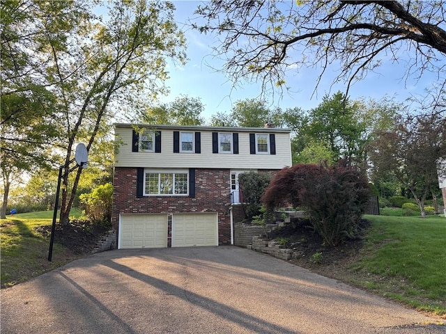 colonial-style house with driveway, brick siding, an attached garage, and a front yard