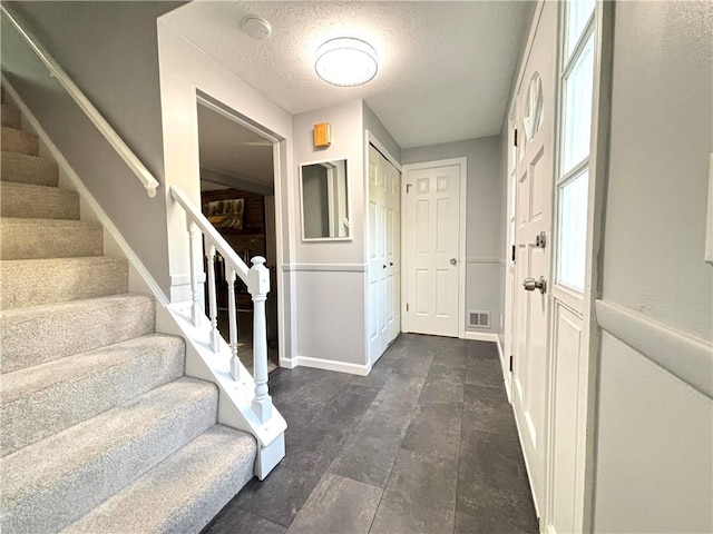 entrance foyer featuring stairway, a textured ceiling, and baseboards