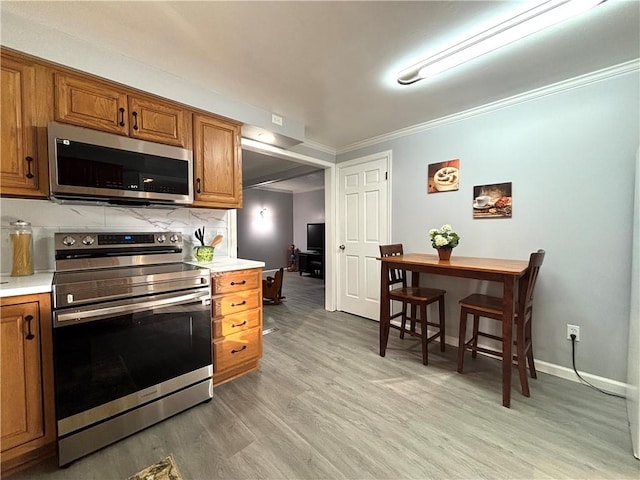 kitchen featuring appliances with stainless steel finishes, brown cabinetry, light wood-style flooring, light countertops, and ornamental molding