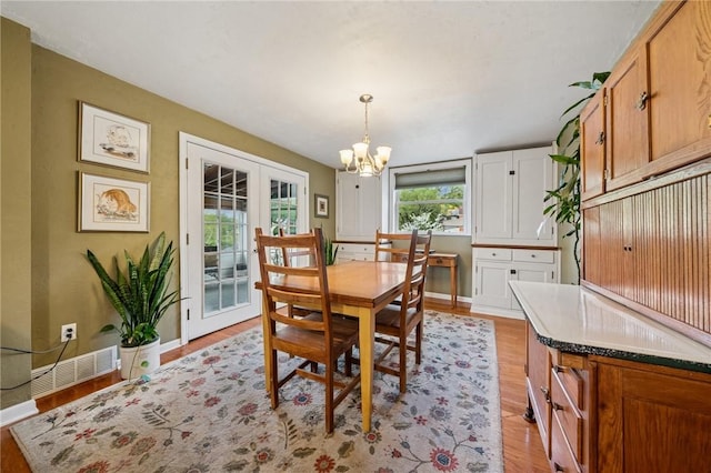 dining space with a chandelier, light wood-type flooring, baseboards, and french doors
