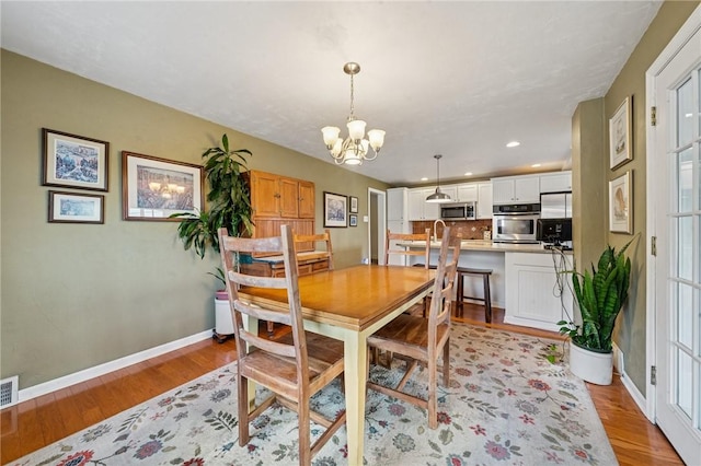 dining space featuring light wood-style flooring, baseboards, a chandelier, and recessed lighting