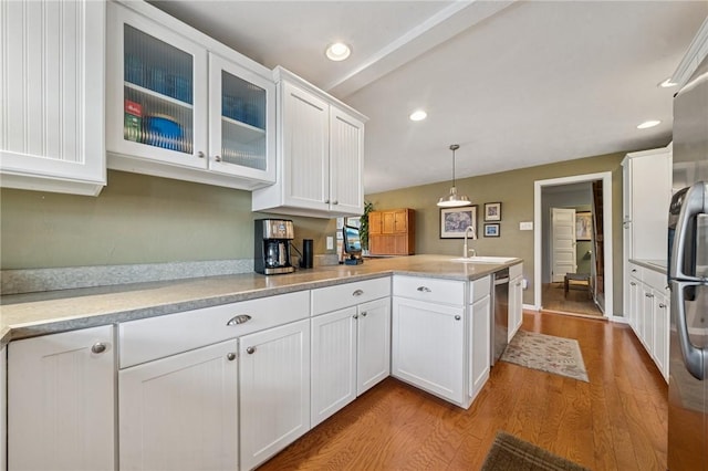 kitchen featuring a peninsula, white cabinetry, a sink, light countertops, and light wood-type flooring