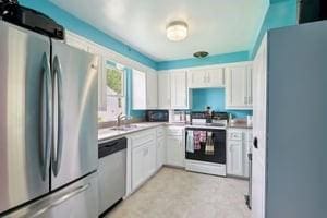kitchen featuring appliances with stainless steel finishes, a sink, white cabinetry, and light countertops