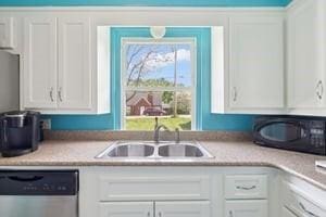 kitchen featuring dishwasher, a sink, white cabinets, and light countertops