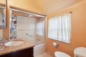 bathroom with toilet, vanity,  shower combination, baseboards, and tile patterned flooring