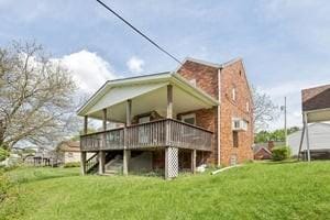 rear view of property featuring a yard, a wooden deck, and stairway