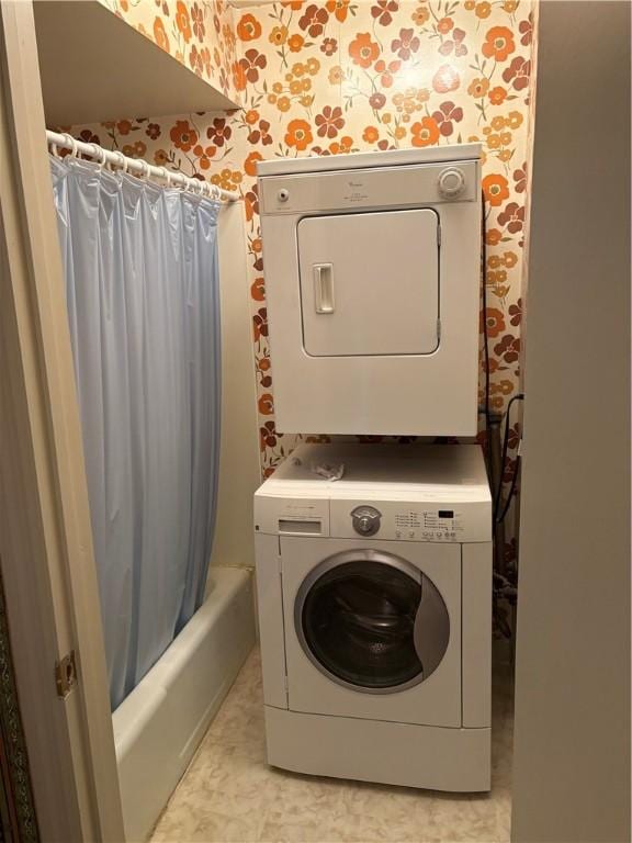 clothes washing area with stacked washer / drying machine and wallpapered walls