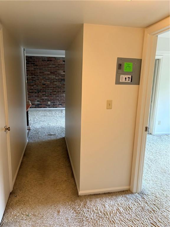 corridor with carpet, brick wall, and baseboards