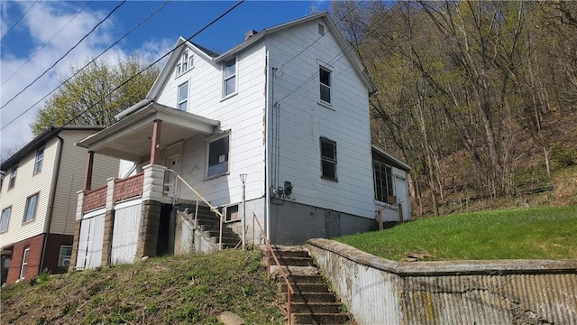 view of home's exterior featuring stairway, covered porch, and a yard