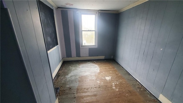 empty room with hardwood / wood-style flooring and wooden walls