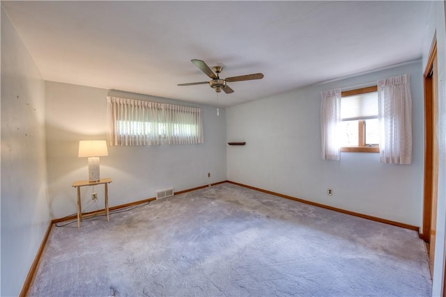 carpeted empty room with ceiling fan and baseboards