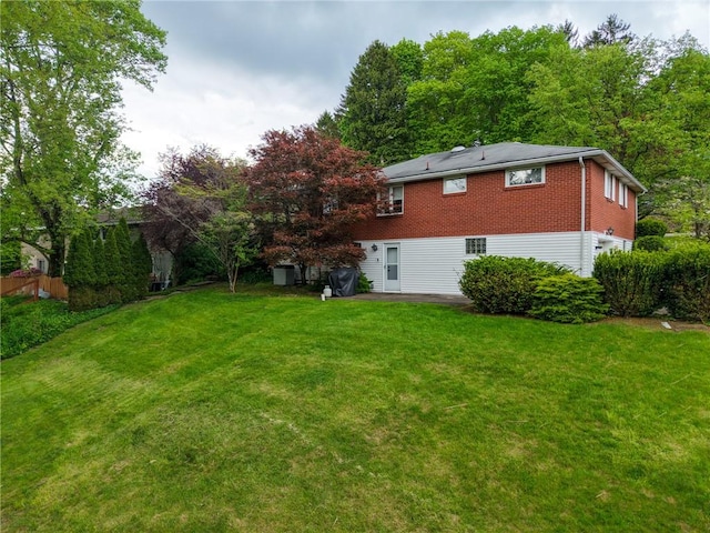 back of property featuring a yard, brick siding, and a patio
