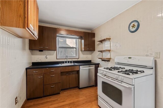 149 Fairfax Rd, Forest Hills Boro, PA 15221 - kitchen with white gas range, stainless steel dishwasher, a sink, light wood finished floors, and dark countertops