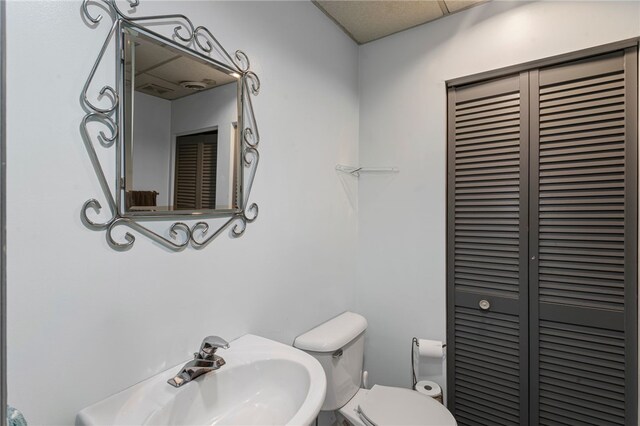half bath with a sink, a closet, and toilet