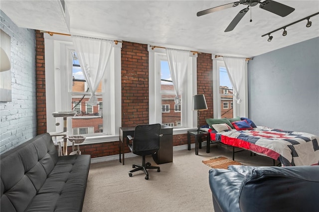 carpeted bedroom with brick wall, a ceiling fan, and rail lighting