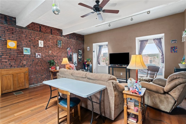 living area with brick wall, light wood-type flooring, ceiling fan, and beam ceiling