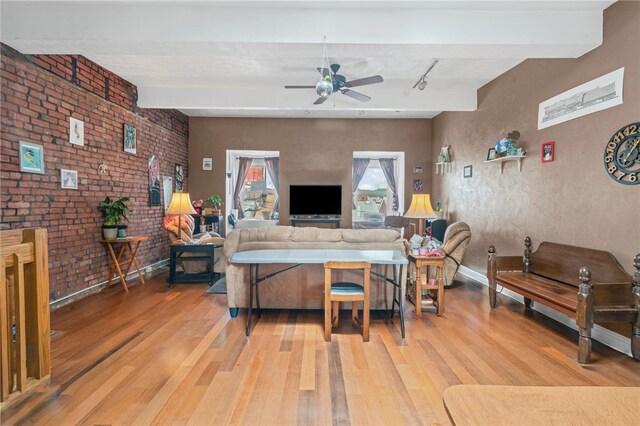living room featuring light wood-style floors, a ceiling fan, beamed ceiling, rail lighting, and baseboards