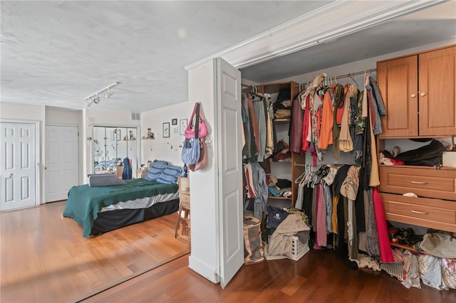 bedroom featuring wood finished floors and rail lighting