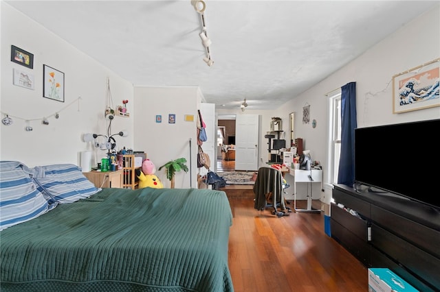 bedroom with track lighting and wood finished floors
