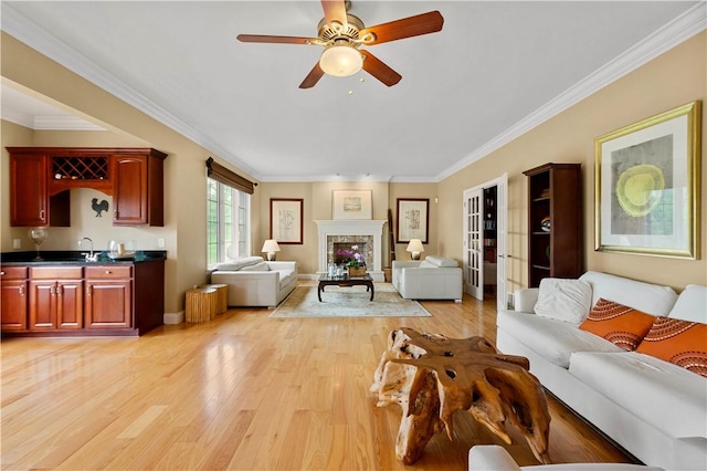 living room featuring light wood finished floors, crown molding, a ceiling fan, wet bar, and french doors