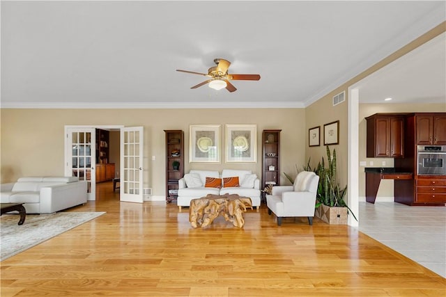 living room with ceiling fan, french doors, ornamental molding, light wood-type flooring, and baseboards