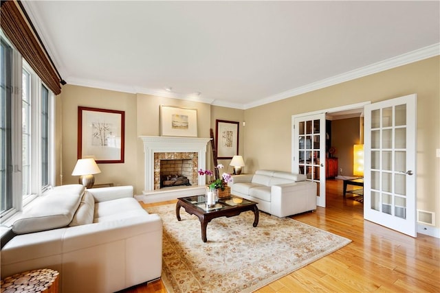 living room featuring french doors, crown molding, light wood-type flooring, and a premium fireplace