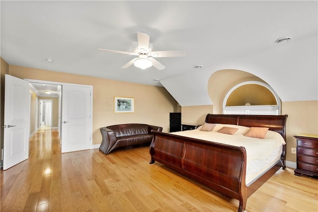 bedroom with light wood-type flooring, ceiling fan, baseboards, and vaulted ceiling