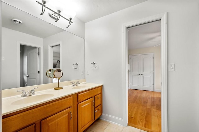 full bathroom featuring baseboards, double vanity, and tile patterned flooring