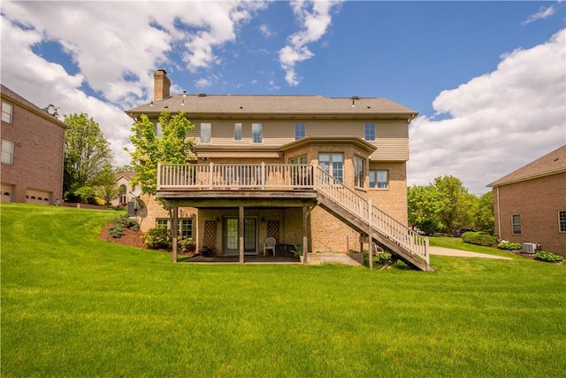 rear view of property with a deck, a chimney, stairs, a lawn, and brick siding