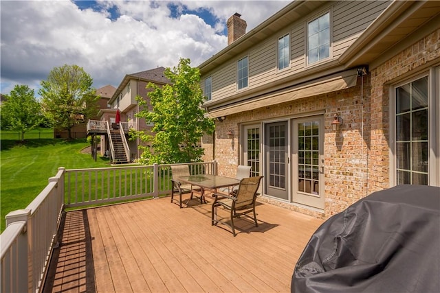 deck featuring outdoor dining area, a grill, and a yard
