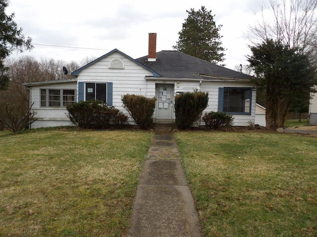 view of front facade with a chimney and a front lawn