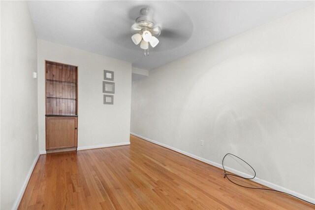 unfurnished room with a ceiling fan, light wood-style floors, and baseboards