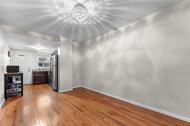 unfurnished room featuring light wood-style floors, baseboards, and a chandelier