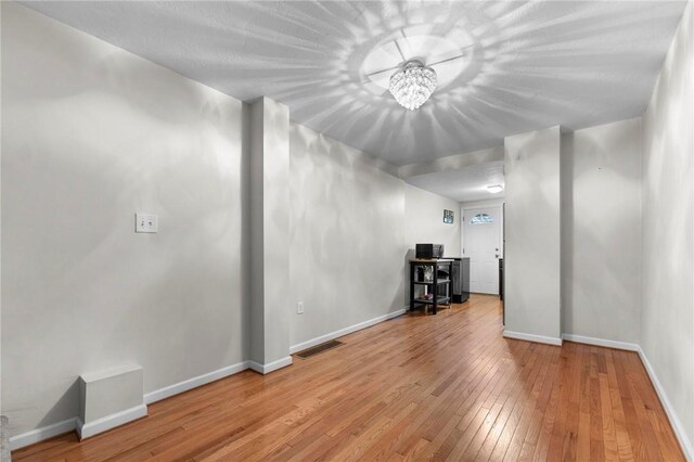 below grade area with wood-type flooring, baseboards, and a chandelier