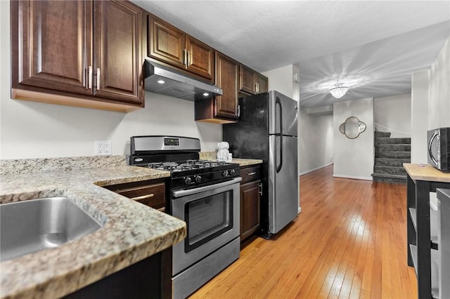 325 Taylor St, Bloomfield, PA 15224 - kitchen with stainless steel appliances, under cabinet range hood, light wood-type flooring, dark brown cabinetry, and light stone countertops