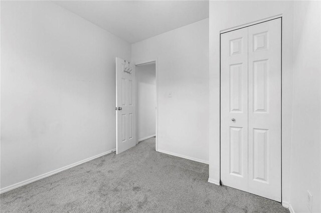 unfurnished bedroom featuring carpet, a closet, and baseboards