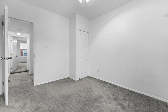 unfurnished bedroom with carpet flooring, baseboards, and a closet