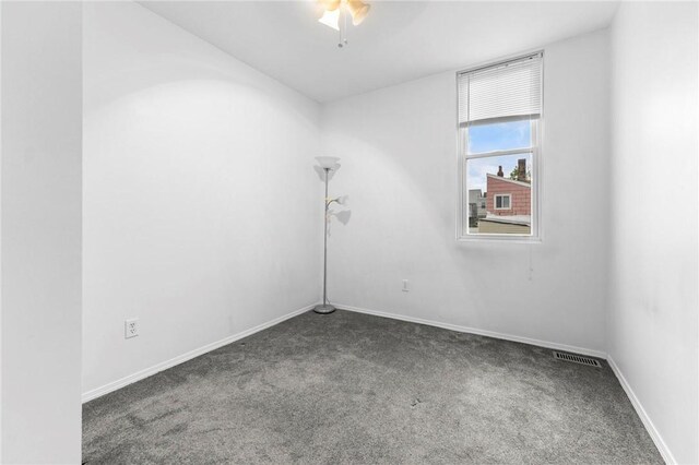 carpeted spare room featuring baseboards and a ceiling fan