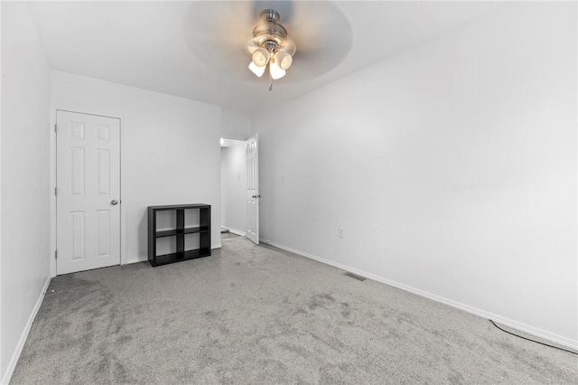 carpeted empty room featuring ceiling fan and baseboards